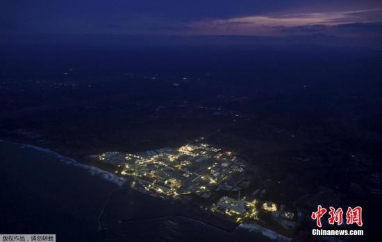 资料图：日本福岛第一核电站在黄昏中停运亮灯的场景。