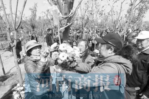 日前，郑州市的一场公益性树葬活动现场，生者给树苗系上黄丝带 记者 邓万里/摄