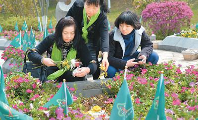 　　图为4月1日，逝者家属在湖北武汉长乐园陵园花坛中的骨灰下葬处撒花瓣。新华社发&nbsp;