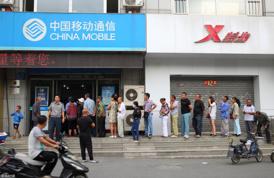 (市民排队办理为手机卡办理实名制 图片来源:视觉中国)