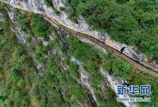 　黄大发沿着陡峭的绝壁巡查、清理水渠(3月24日摄)。新华社记者 刘续摄 