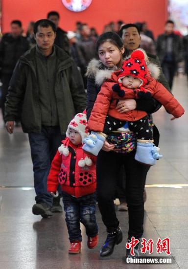 资料图：2月3日，山西太原火车站，一名旅客带着她的两个孩子返乡过年。。中新社记者 韦亮 摄