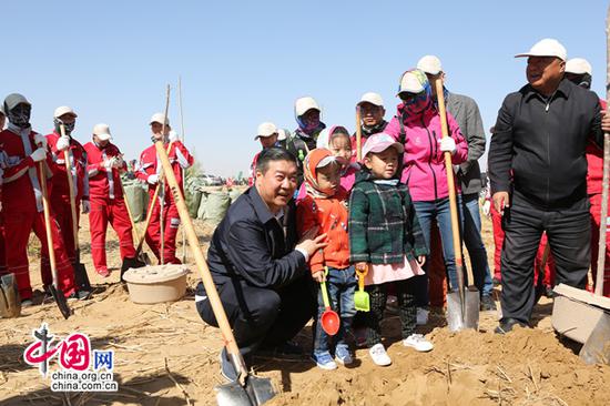 亿利资源集团董事长王文彪与参加植树的少年儿童一起植树