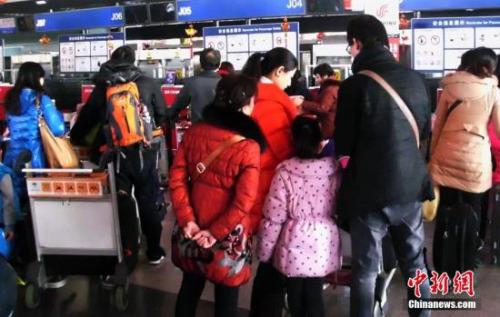 北京首都国际机场的乘客在排队办理登机手续。（资料图）中新社发 钱兴强 摄