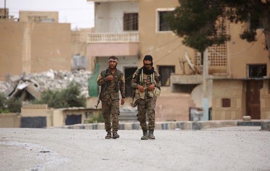  2017年5月18日，在叙利亚拉卡附近的塔卜卡镇，两名“叙利亚民主军”士兵走在街道上。（新华/法新）