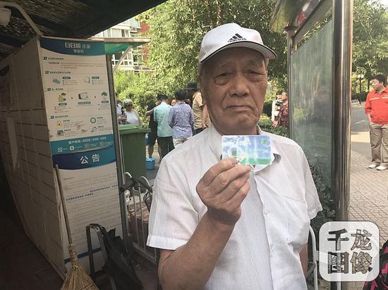 天香颐中里小区的每户居民家里都配有物业发放的厨余垃圾桶,小区里还设置了厨余垃圾投放站,由专门的工作人员监管,并为居民们投放的垃圾称重,刷卡积分。图为小区居民展示积分卡。千龙网记者 戴琪摄