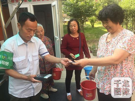 天香颐中里小区的每户居民家里都配有物业发放的厨余垃圾桶,小区里还设置了厨余垃圾投放站,由专门的工作人员监管,并为居民们投放的垃圾称重,刷卡积分。图为小区厨余垃圾投放站管理员为居民刷卡积分。千龙网记者 薄晨棣摄