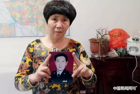  张学林之妻吕爱平拿着丈夫的照片怅然若失。摄影|《中国新闻周刊》记者周群峰 