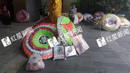 ▲事发小区内堆满进行祭奠的花圈、鲜花、死者照片  图片来源：红星新闻