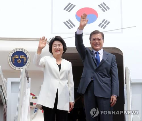 6月28日下午，韩国总统文在寅（右）与夫人金正淑女士搭乘赴美专机前向欢送人群挥手致意。（韩联社）