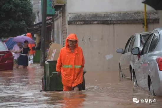 图为7月1日，环卫工人在长沙城区一处积水的社区涉水前行。新华社记者 龙弘涛 摄