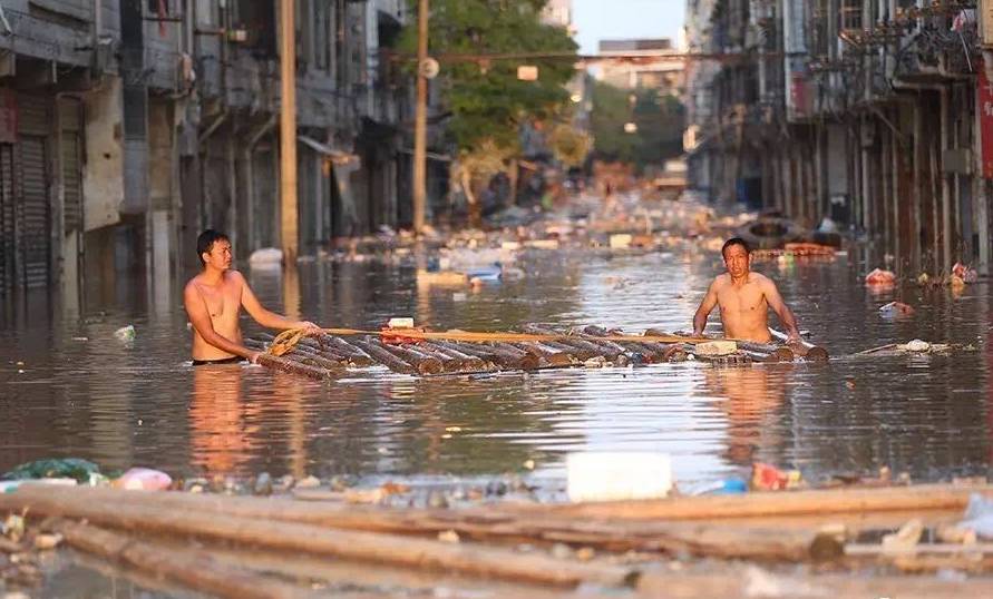  7月2日下战书6时，宁乡市，沙河市场内，两名上身赤裸的商户在水中打捞建材。