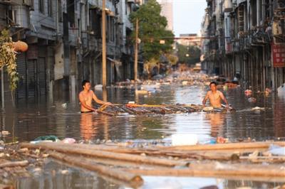  7月2日，宁乡沙河市场内，两名上身赤裸的商户在水中打捞建材。 
