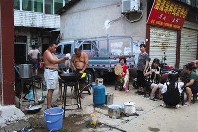  7月2日，宁乡群英路，因家中被水浸泡，以及停水停电，几家人在路边架锅做晚饭。 