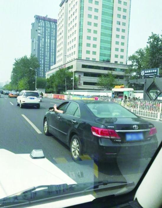 司機在中關村南大街駕車時將左腳伸出窗外。