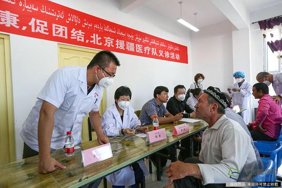 7月10日，来自北京市18位医务工作者到新疆和田洛浦县恰尔巴格村，为这里的村民展开爱心义诊活动。图为北京市援疆医生询问患者病情。记者 许珠珠摄