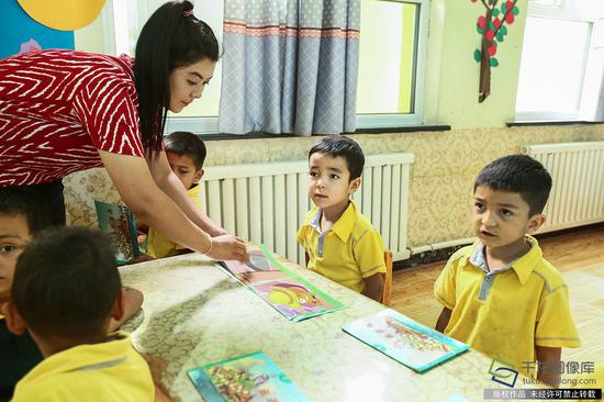 和田市赛其阿克塔什北京幼儿园的老师在给小朋友上课（7月7日摄 图片来源：tuku.qianlong.com）。千龙网记者 许珠珠摄