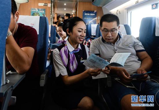 在上海虹桥站开往郑州东站的G1802次列车上,乘务员夏梦雅给乘客发放宣传资料,讲解注意事项(2016年9月10日摄)。新华社记者季春鹏摄