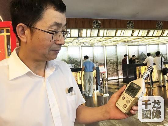 温度调高一度,一天可以节电1500度左右,一年供冷季约可节电18万度,折合人民币约15万元。图为北京国际饭店工程部空调系统部经理刘学军测量大堂内的温度为26.1度。千龙网记者 查甜甜摄