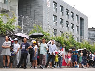  北京大学东侧围墙外，游客排起长队。围墙上安装了两层铁丝网。