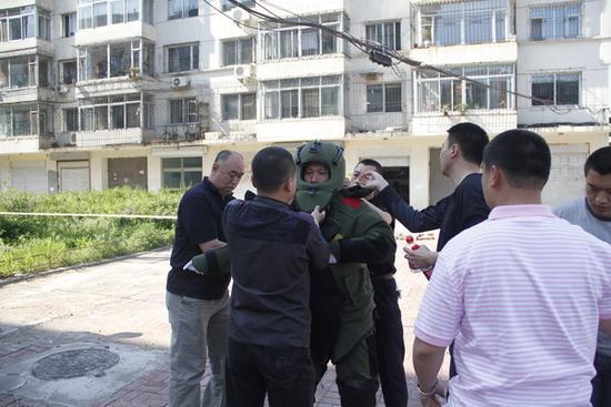 成功排爆后,同事们正在帮朱建民脱下防爆服,防爆服重达70斤。
