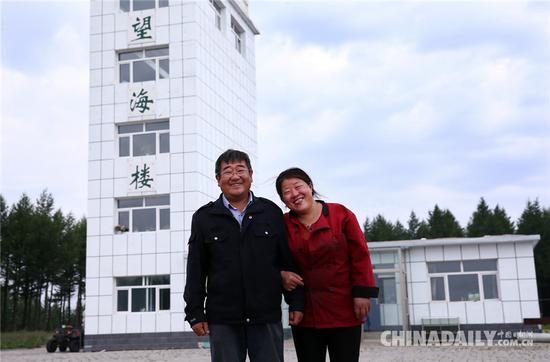 望火员刘军与爱人在一起。从他们身后的望海楼(望火楼)向远方眺望,是无际的林海。