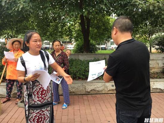 曹静拖着骨折的伤腿，在湖南浏阳洞阳集镇街头向路人发放寻人启事。智慧浏阳 图
