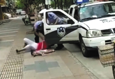 民警将该女子摔倒在地，其怀中儿童跌落。视频截图