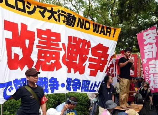 8月6日，在日本广岛原子弹爆炸遗址前，民众手持标语参加集会，抗议首相安倍晋三出席纪念仪式，要求安倍下台。（新华社记者马平摄 ）