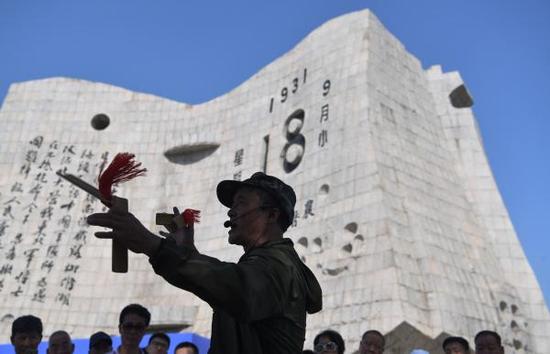 2017年9月18日，辽宁沈阳，“九一八纪念馆”前，有一位民间说书人用快板书在讲述着九一八事变的始末。  东方IC 图