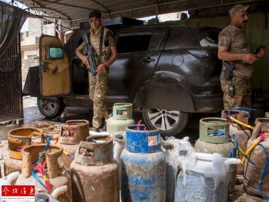 资料图：伊拉克政府军士兵正在检查缴获的被极端组织用来制造汽车炸弹的煤气罐。