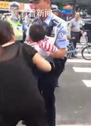 警察上前抱起孩子，却又被妇女夺回，重新放到了地上，大声叫嚷。