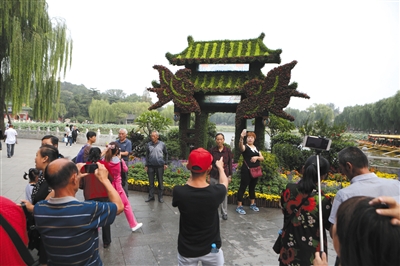 9月25日，北海公园南门，提前开始享受假期的游客在“双燕报喜”主题花坛前拍照留念。新京报记者 侯少卿 摄
