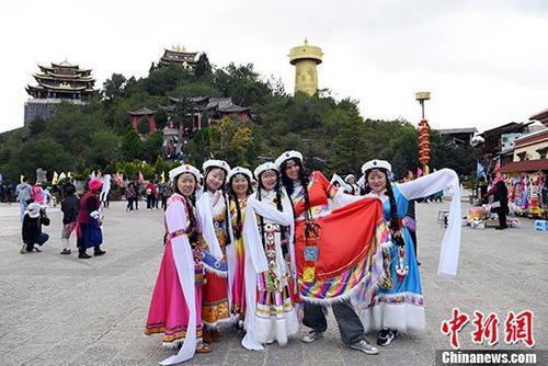 10月3日，着藏族服饰的游客在独克宗古城月光广场上合影。 中新社记者 李进红 摄