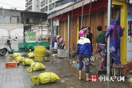 15日白天，广东湛江风雨逐渐明显，市民正在加固门窗。（图/殷美祥）