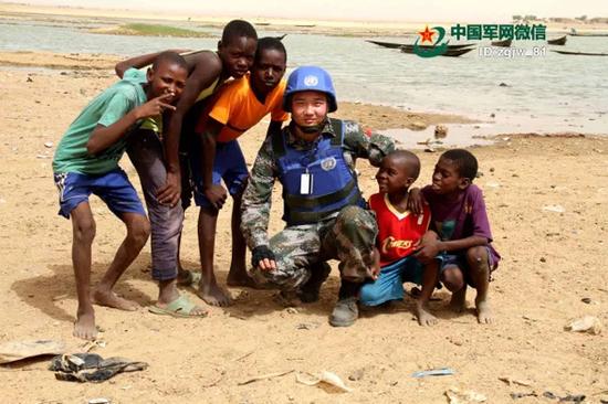 2015年7月1日,作者在尼日尔河畔与当地儿童合影。 中国军网 资料图