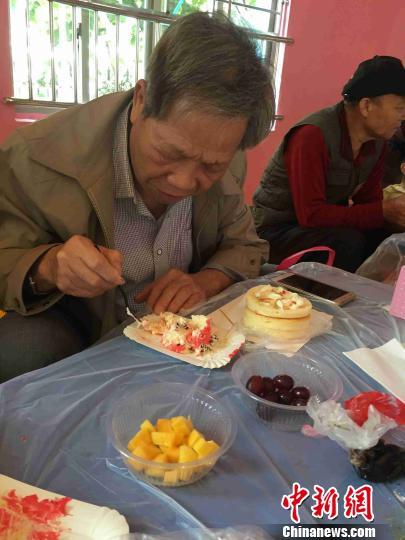 图为一名老爷爷在品尝自己亲手制作的蛋糕。 周潇男 摄