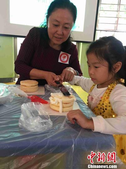 图为一名空巢老人与凤起新都幼儿园小朋友一起做蛋糕。　周潇男 摄