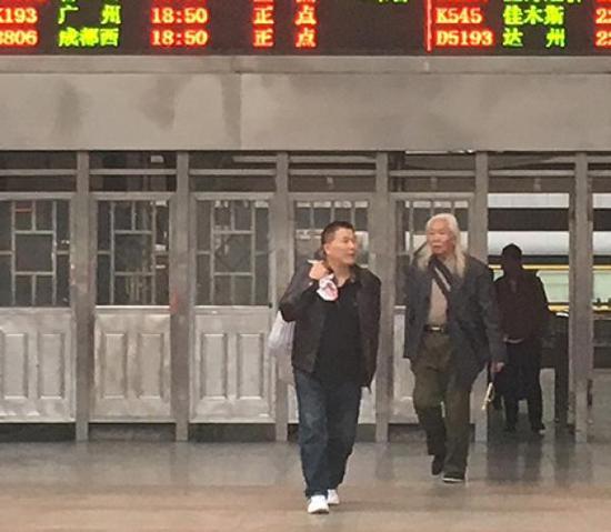 11月10日17时20分许，黄云彪在两名男子陪同下走出成都火车站出站口，帮他背塑料袋的男子称不认识黄云彪。澎湃新闻记者 王万春 图