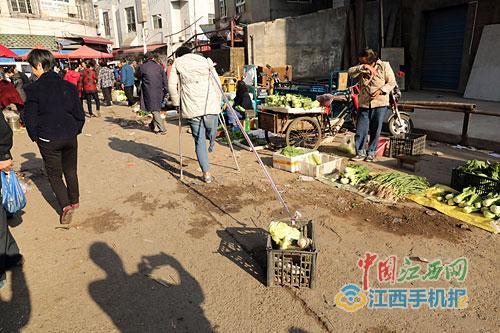 11月12日清晨，乐平市西门菜市场，15岁的女孩程瑶瑶拄着拐，称菜、收钱、找零……稚嫩的脸蛋与娴熟的卖菜动作并不相符。