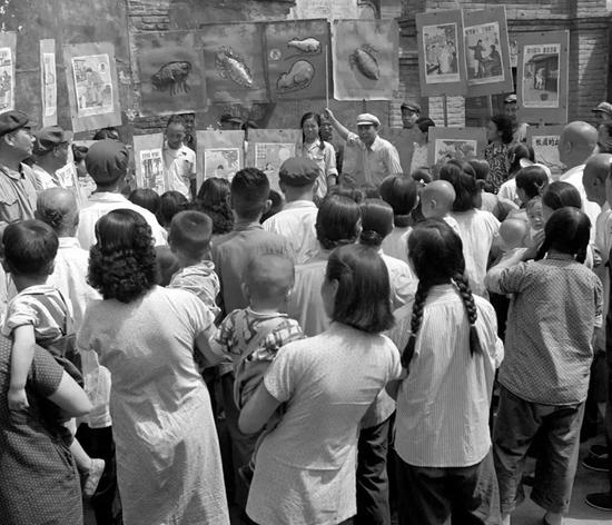 1953年6月,北京前炒面胡同爱国卫生运动委员会分会宣传队正在向群众讲解蚊、蝇怎样传染疾病。图源:毛松友|新华社