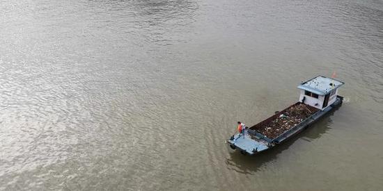 ↑7月30日，重庆市巫山县九码头附近江面，环卫工人正在清理江面漂浮垃圾。新华社记者 金立旺 摄