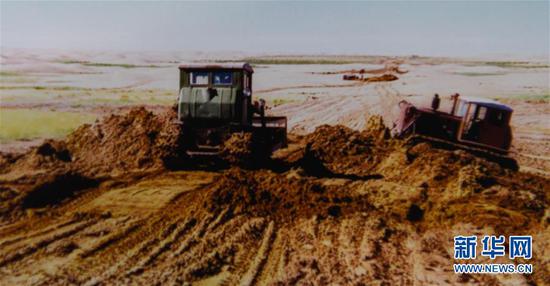 这是内蒙古鄂尔多斯市杭锦旗库布其沙漠生态科技中心展览馆保存的20世纪90年代杭锦旗人民修建“锡乌”穿沙公路的照片（翻拍照片）。新华社发