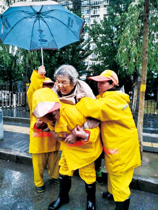 北京市公共文明引导员总队是2018年度北京榜样，图为引导员们在东三旗南北行站雨中帮助摔伤老人。 中共北京市委宣传部供图