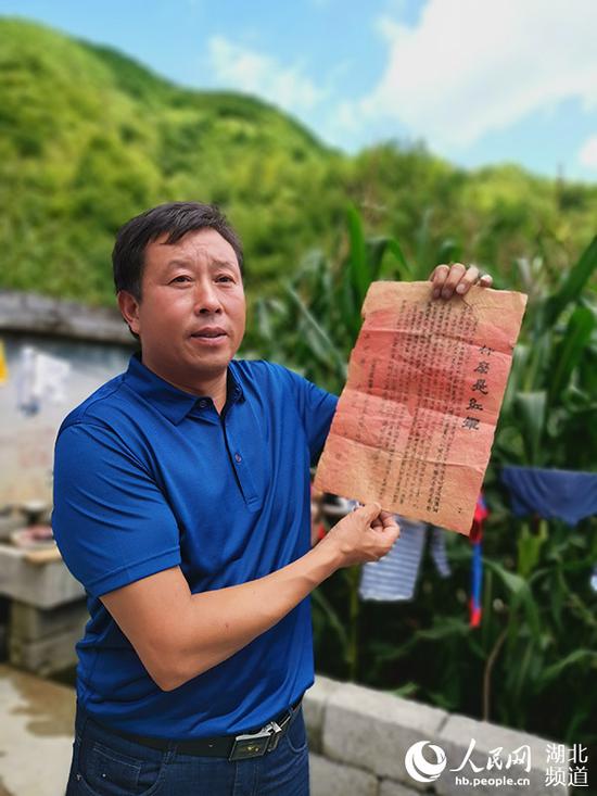 李登科展示他家珍藏的《什么是红军》宣传单的复刻版。(周雯 摄)