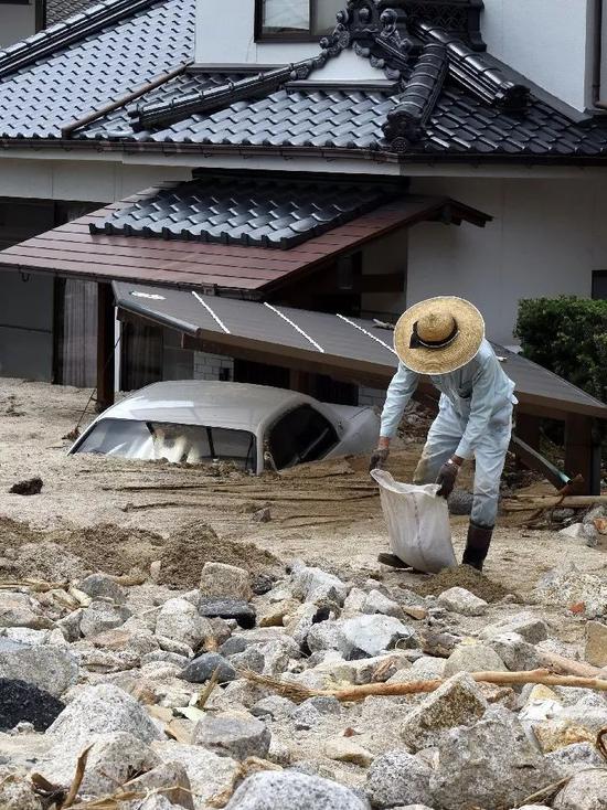 7月11日，在日本廣島吳市天應西條地區，居民清理被泥石流淹沒的房屋。（新華社記者馬平攝）