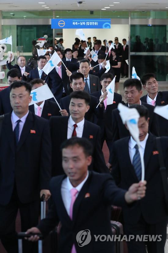 8月10日,朝鲜代表团抵达韩国,挥舞统一旗。(韩联社)