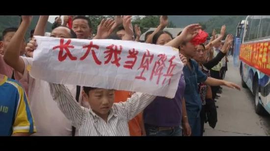 △2008年,汶川地震后,程强举起“长大我当空降兵”的标语。