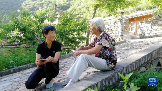 刘桂珍（左）和村民聊家常（2022年7月6日摄）。新华社发