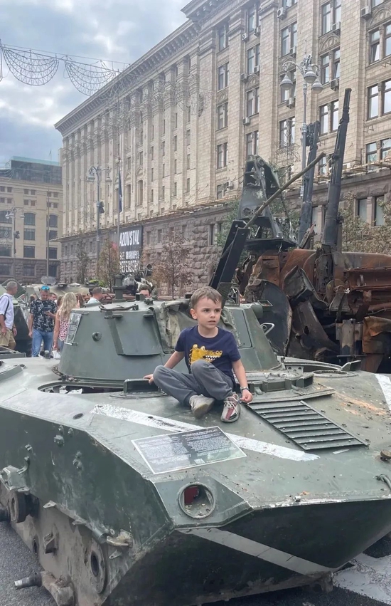 一个乌克兰孩子坐在停在基辅的一辆装甲车残骸上。图源：推特